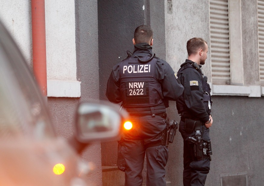 26.10.2022, Nordrhein-Westfalen, Duisburg: Polizisten stehen vor einem Haus, in dem sie eine Wohnung durchsucht haben. Die Razzia im Clan-Milieu findet in drei St