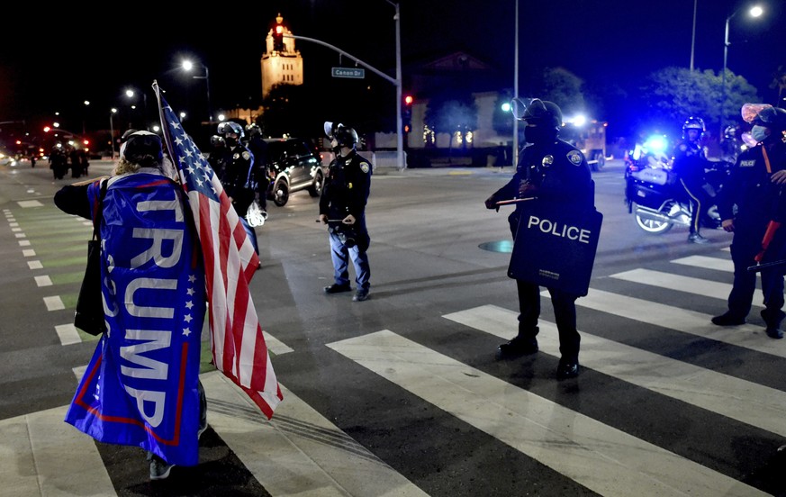 A protester carrying a flag in support of President Donald Trump and an American flag yells toward Beverly Hills Police as the authorities declare the protest an unlawful assembly and attempt to clear ...