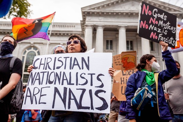 July 26, 2022, Washington, DC, United States: An anti-Trump protester displays a placard calling Christian nationalists fascists while demonstrating against Trump s speech at an America First conferen ...