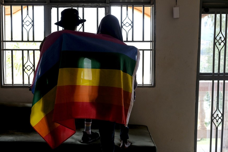 FILE - A gay Ugandan couple cover themselves with a pride flag as they pose for a photograph in Uganda on March 25, 2023. Uganda&#039;s president Yoweri Museveni has signed into law tough new anti-gay ...