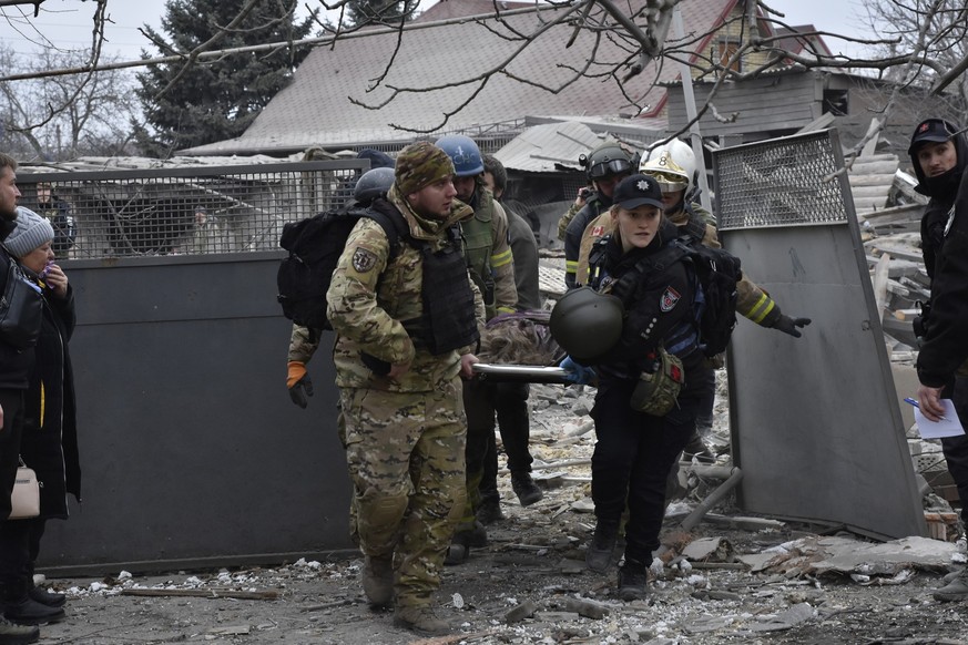 Ukrainian emergency workers and servicemen carry the body of a resident killed in Russia&#039;s massive air attack in Zaporizhzhia, Ukraine, Friday, Dec. 29, 2023. (AP Photo/Andriy Andriyenko)