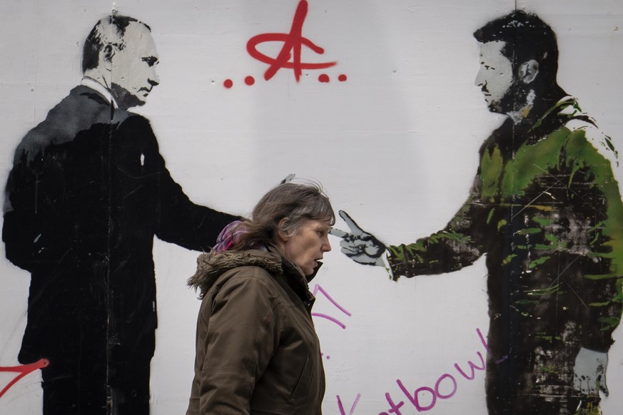 04.05.2023, Großbritannien, London: Eine Frau geht an einem Graffiti vorbei, das den ukrainischen Präsidenten Selenskyj (r) und den russischen Präsidenten Putin darstellt. Foto: Vadim Ghirda/AP/dpa ++ ...