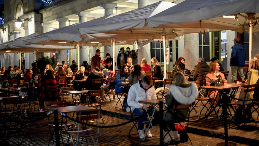 People sit at tables in Covent Garden, in London, Saturday, Dec. 12, 2020. Health Secretary Matt Hancock says infections are starting to rise in some areas after falling during a four-week national lo ...