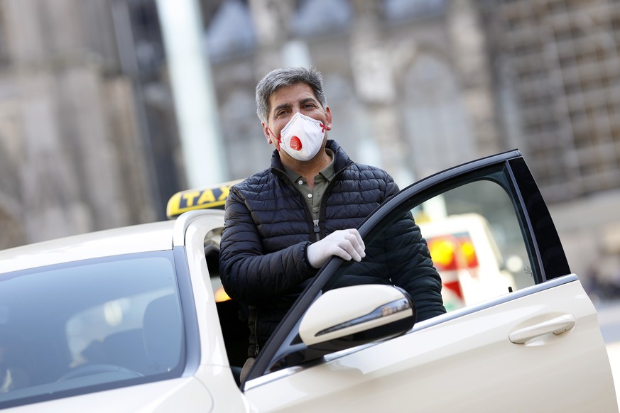 Wie lange wird dieser Anblick noch zu unserem Alltag gehören? Ein Kölner Taxifahrer trägt Mundschutz und Handschuhe.