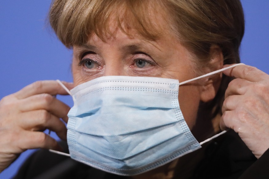 FILE-In this March 30, 2021 taken photo German Chancellor Angela Merkel puts on her face mask after she briefs the media following a virtual meeting with federal state governors at the chancellery in  ...