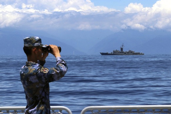 FILE - In this photo provided by China&#039;s Xinhua News Agency, a People&#039;s Liberation Army member looks through binoculars during military exercises as Taiwan&#039;s frigate Lan Yang is seen at ...
