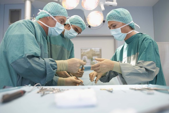 Three Surgeons At Work In Operating Theatre, model released, , 9999668.jpg, Cooperation, Teamwork, Expertise, Indoors, Adult, Woman, Concentration, Side View, Room, Occupation, Working, Medicine, Heal ...