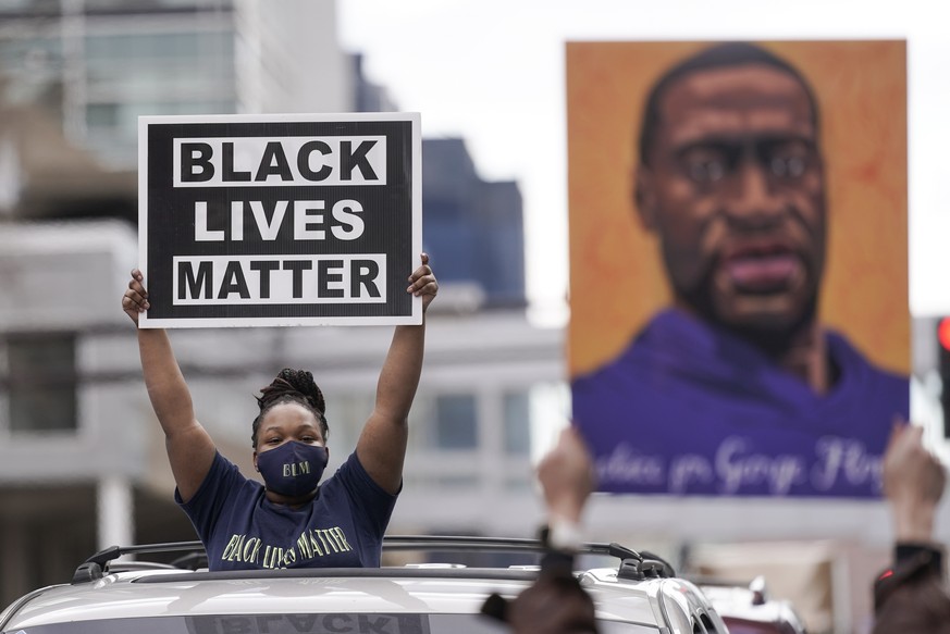 People hold signs, including one with an image of George Floyd, outside the courthouse in Minneapolis on Tuesday, April 20, 2021, after the guilty verdicts were announced in the murder trial of former ...