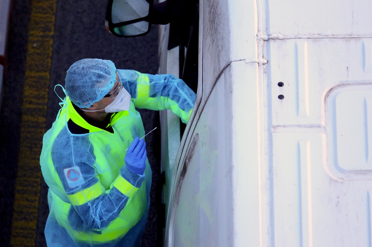24.12.2020, Großbritannien, Dover: Ein Mann führt einen Corona-Test bei einem in einem LKW sitzenden Fahrer durch. Die britische-französisch Grenze soll über die Weihnachtsfeiertage offen bleiben und ...