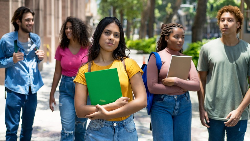 Young mexican female student with group of latin american and caucasian and african young adults outdoor in city