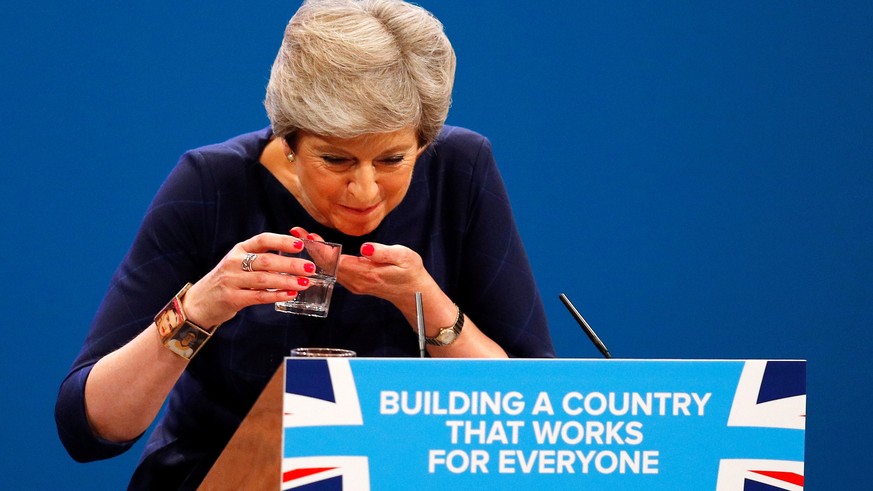 FILE PHOTO: Britain's Prime Minister Theresa May struggles with her glass of water after suffering a coughing fit whilst addressing the Conservative Party conference in Manchester, October 4, 2017. To ...