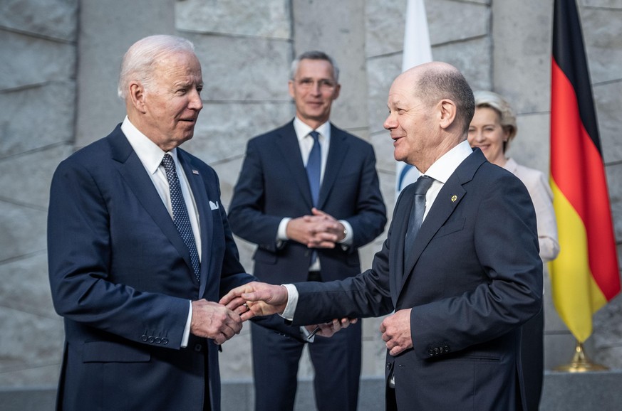 Bundeskanzler Olaf Scholz (r, SPD), begrüßt Joe Biden (l), Präsident der USA, vor Beginn des Treffens der G7-Staaten im Nato-Hauptquartier. Im Hintergrund stehen Jens Stoltenberg, Nato-Generalsekretär ...