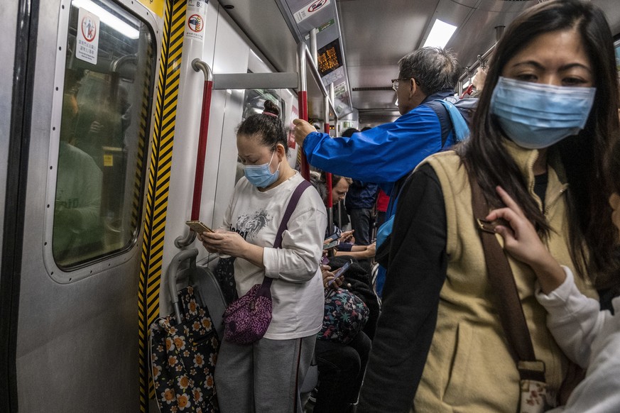 Menschen in Hongkong tragen eine Gesichtsmaske in der U-Bahn. Zur Stadt Wuhan wurden unterdessen Bahn- und Flugverbindungen gekappt.