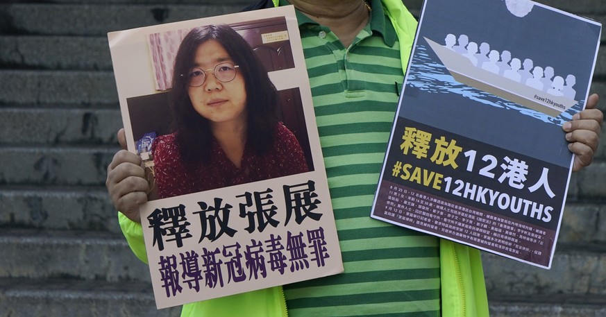 A pro-democracy activist holds placards with the picture of Chinese citizen journalist Zhang Zhan outside the Chinese central government&#039;s liaison office, in Hong Kong, Monday, Dec. 28, 2020. Zha ...