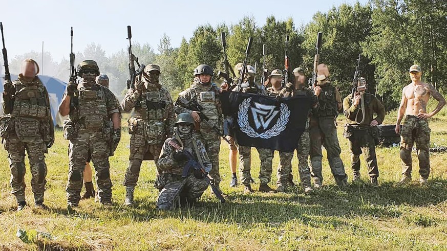 Neonazis der Taskforce Russitsch mit einer Valknut-Flagge, die mit der nationalsozialistischen Bewegung in Verbindung gebracht wird.