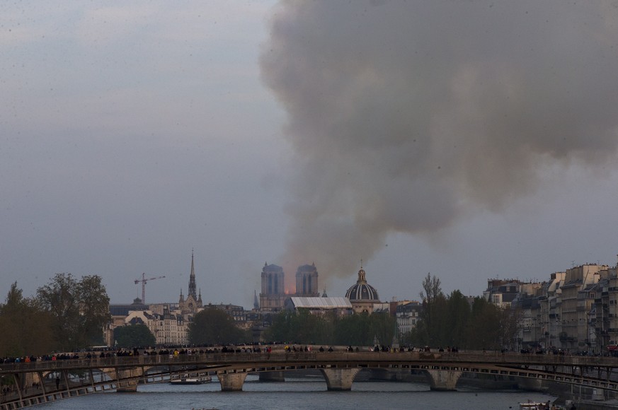 Flames and plumes of smoke rise from Notre Dame cathedral as it burns in Paris, Monday, April 15, 2019. Massive plumes of yellow brown smoke is filling the air above Notre Dame Cathedral and ash is fa ...
