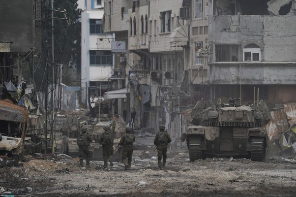 22.11.2023, Palästinensische Gebiete, Gaza-Stadt: Israelische Soldaten gehen eine Straße entlang während einer Bodenoperation im Gazastreifen. Foto: Victor R. Caivano/AP/dpa +++ dpa-Bildfunk +++