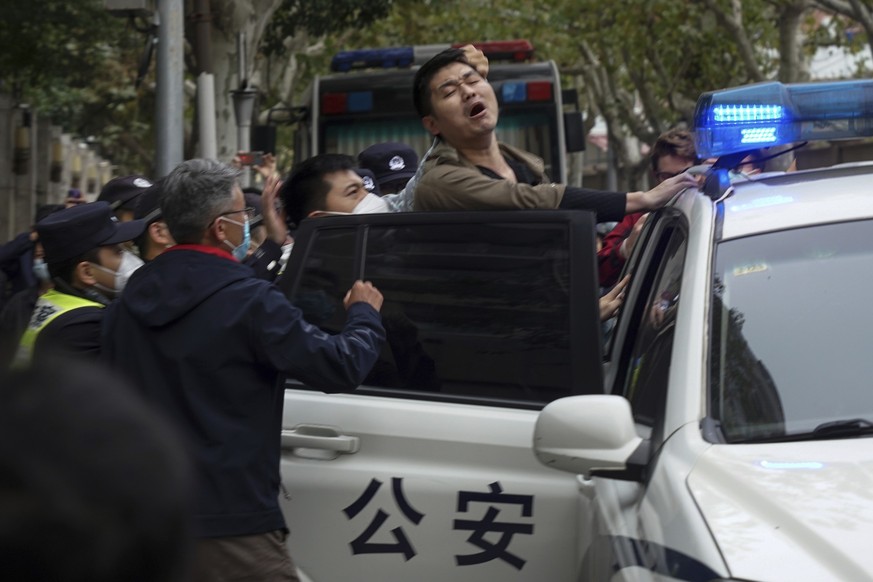 28.11.2022, China, Shanghai: Auf diesem Foto vom Sonntag, 27. November 2022, reagiert ein Demonstrant, als er bei einem Protest von Polizisten festgenommen wird. W