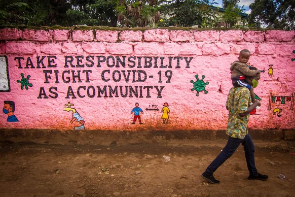 News Bilder des Tages May 9, 2020: A man carrying his child are seen matching their way past a local wall filled with the Corona Virus safety information. - ZUMAd156 20200509zipd156008 Copyright: xDon ...