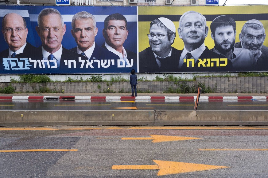 An Ultra-Orthodox Jewish man looks at an elections billboards of the Blue and White party leaders, from left to right, Moshe Yaalon, Benny Gantz, Yair Lapid and Gabi Ashkenazi, alongside a panel on th ...