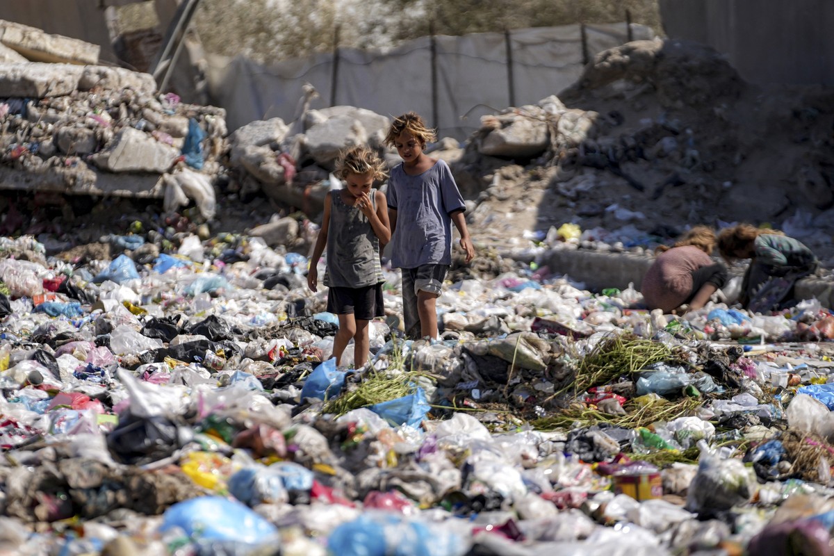 Displaced kids sort through trash at a street in Deir al-Balah, central Gaza Strip, Thursday, Aug. 29, 2024. (AP Photo/Abdel Kareem Hana)