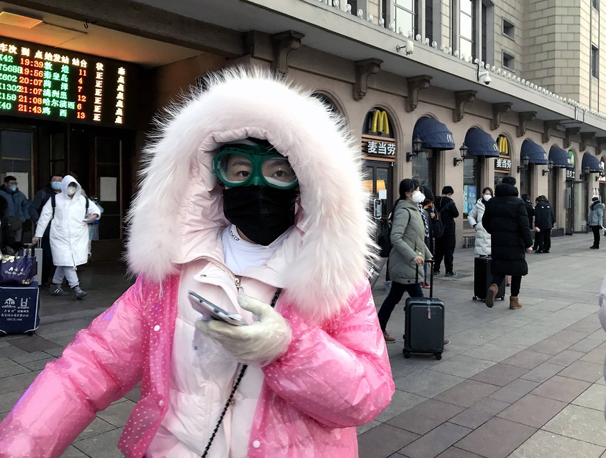 Eine Frau in Peking trägt Mundschutz, eine Taucherbrille und Plastikhandschuhe, um sich vor einer Infektion mit dem Coronavirus zu schützen.