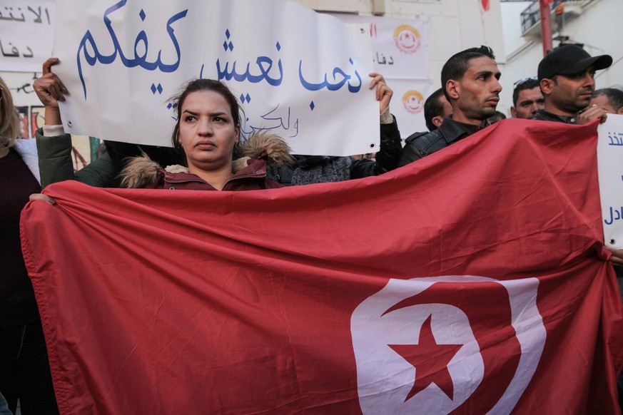 A UGTT UNIONIST HOLDING FLAG OF TUNISIA DURING CELEBRATIONS OF 9TH ANNIVERSARY OF THE REVOLUTION Unionists holding the flag of Tunisia and a placard which reads, I want to live like you, but with dign ...