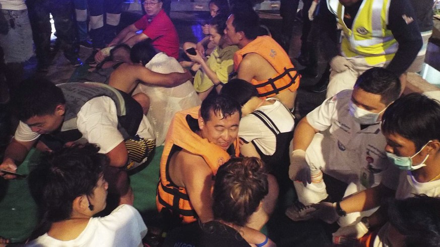 Rescued tourists from a boat that sank gather on a pier Thursday, July 5, 2018, on the island of Phuket, southern Thailand. A boat carrying dozens of Chinese tourists overturned in rough seas off sout ...