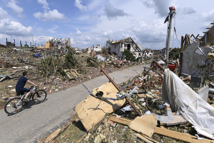 Man rides his bike after a tornado hit the village of Mikulcice in the Hodonin district, South Moravia, Czech Republic, Friday, June 25, 2021. A rare tornado tore through southeastern Czech Republic,  ...