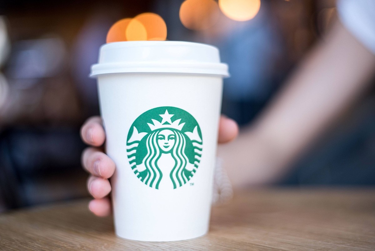 03.10.2017, xfux, Wirtschaft, Restaurant / Kaffee Starbucks Coffee in Madrid in der Calle de la Princesa 42, emwirt emonline, v.l. Eine Frau haelt einen weißen Papierbecher / Becher mit Kaffee gefuell ...