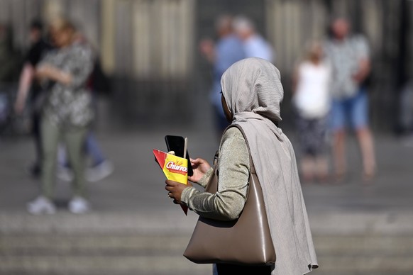 Eine schwarze Frau mit Kopftuch schaut auf ihr Handy. In Deutschland leben knapp 95.000 Menschen, deren Staatsangehörigkeit als ungeklärt gilt. Themenbild, Symbolbild Köln, 11.06.2023 NRW Deutschland  ...