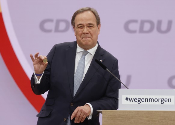 North Rhine-Westphalia's Governor and candidate as leader of the Christian Democratic Union (CDU) Armin Laschet shows a luck coin offered to him by his father as he delivers his speech on the second d ...