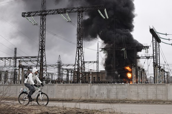 ARCHIV - 22.03.2024, Ukraine, Charkiw: Ein Mann radelt nach einem russischen Angriff an einem Elektrizitätswerk vorbei. Durch einen der heftigsten Luftangriffe in mehr als zwei Jahren Angriffskrieg ha ...