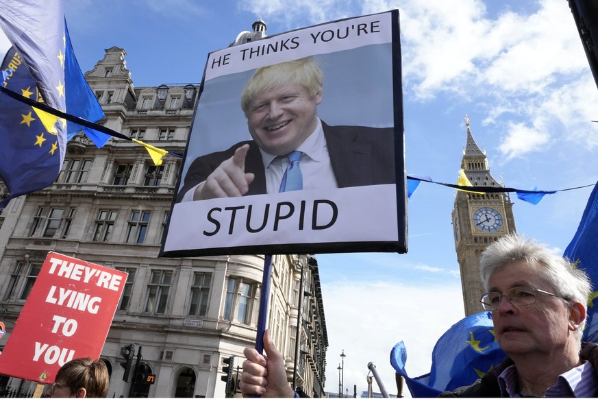 Protestors show placards as they demonstrate near Parliament in London, Wednesday, March 22, 2023. Britain&#039;s former prime minister Boris Johnson faces a grilling Wednesday by a committee of lawma ...