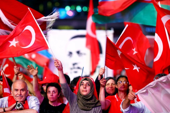 FILE PHOTO: Supporters of Turkish President Recep Tayyip Erdogan wave national flags as they listen to him through a giant screen in Istanbul's Taksim Square, Turkey, August 10, 2016. REUTERS/Osman Or ...