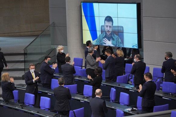 Der ukrainische Präsident Wolodymyr Selenskyj spricht auf einer Videoleinwand im Bundestag und bekommt Applaus von der Bundesregierung.