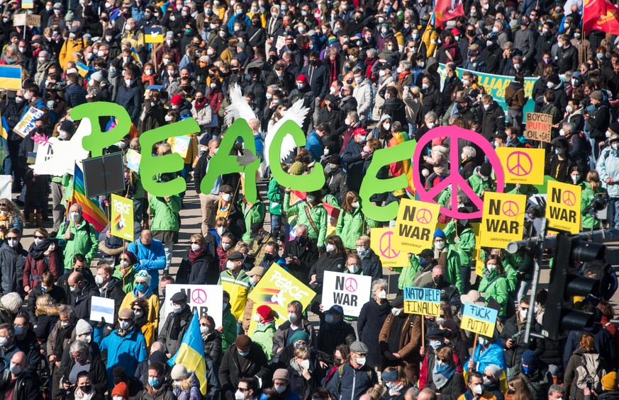 Teilnehmer einer Demonstration gegen den Ukraine-Konflikt stehen auf dem Jungfernstieg und halten das Wort «Peace».