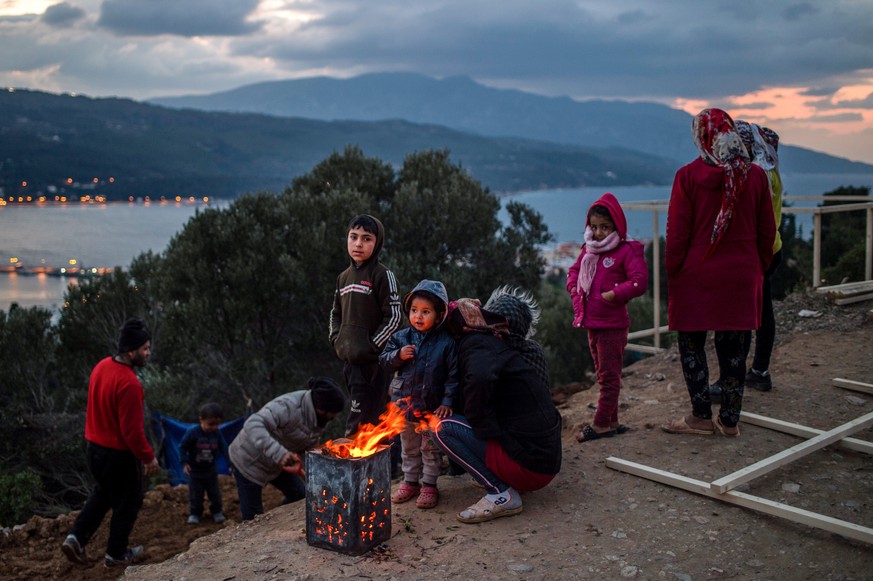 22.02.2020, Griechenland, Samos: Fl�chtlinge w�rmen sich in einem Fl�chtlingslager am Lagerfeuer. Die griechische Regierung baut auf der Insel Samos ein neues Camp f�r Fl�chtlinge. In dem Lager sollen ...