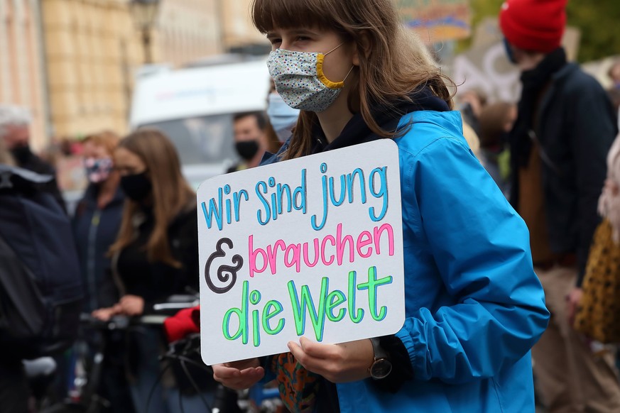 Eine Frau mit Schild Wir sind jung und brauchen die Welt w