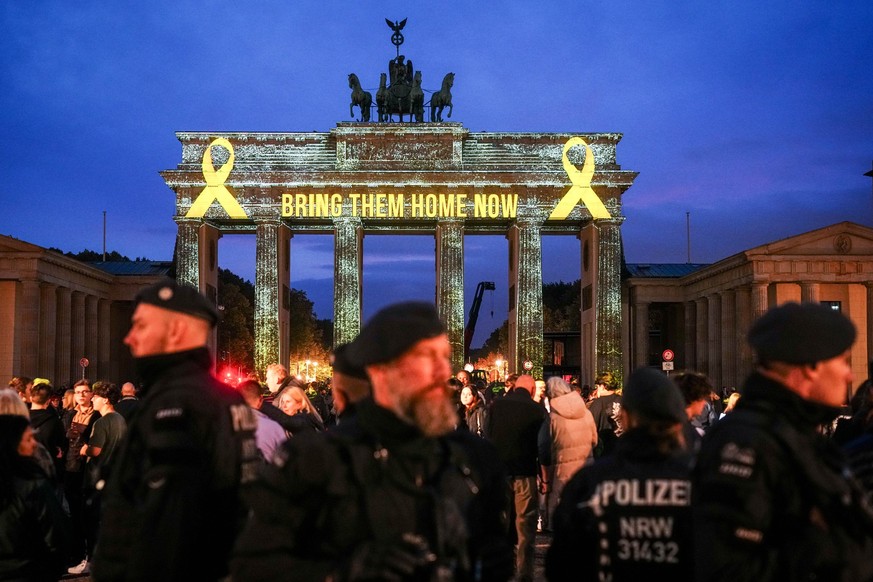 07.10.2024, Berlin: Der Schriftzug «Bring them home now» (Bringt sie jetzt nach Hause) ist auf dem angestrahlten Brandenburger Tor anlässlich des Jahrestags des Hamas-Angriffs auf Israel vom 7. Oktobe ...