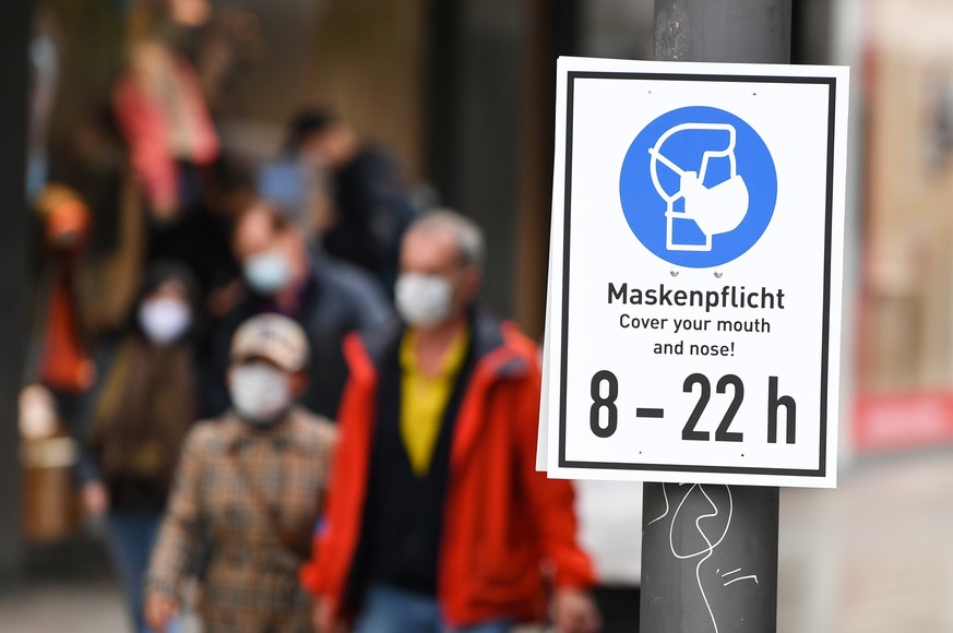 ARCHIV - 28.10.2020, Hessen, Frankfurt/Main: Ein Schild mit der Aufschrift &quot;Maskenpflicht. Cover your mouth and nose! 8 - 22 h&quot; ist auf der Frankfurter Einkaufsmeile Zeil an einem Mast angeb ...