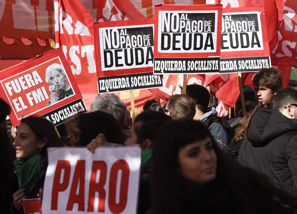 Political parties opponents and social movements protesters hold signs that read in Spanish: "Out IMF and No to the payment of the debt, " one showing an image of with a picture of Christine ...