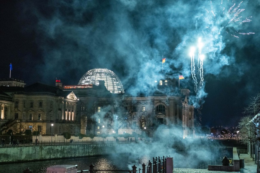 31.12.2022, Berlin: An der Spree vor dem Reichstagsgebäude wird Feuerwerk abgebrannt. Foto: Christophe Gateau/dpa +++ dpa-Bildfunk +++
