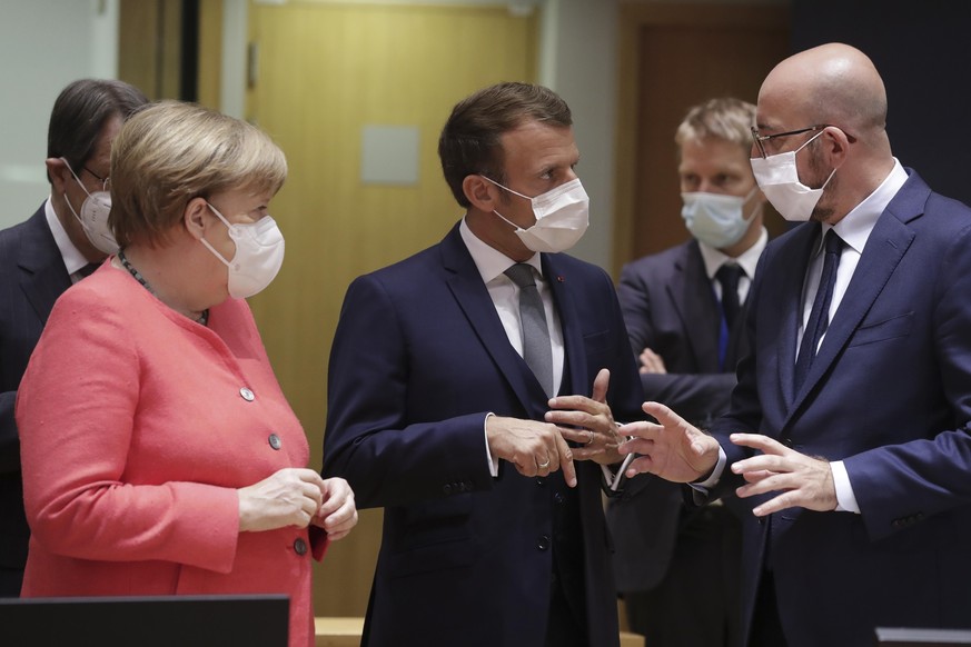 German Chancellor Angela Merkel, left, speaks with French President Emmanuel Macron, center, and European Council President Charles Michel, right, during a round table meeting at an EU summit in Bruss ...