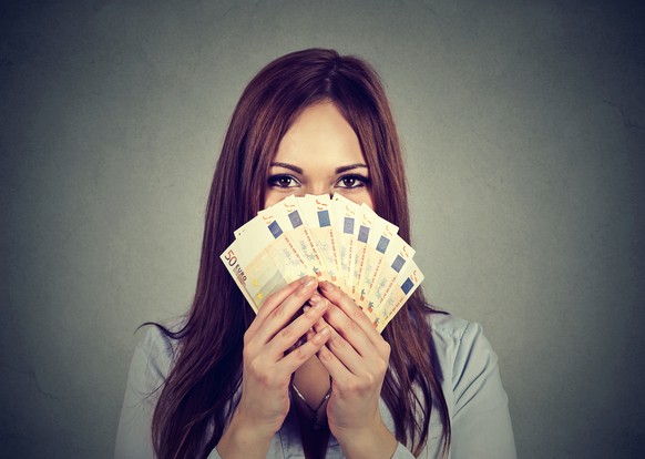 Young woman hiding her face behind euro money fan