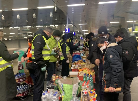 Freiwillige Helferinnen und Helfer verteilen Lebensmittel an Menschen aus der Ukraine am Berliner Hauptbahnhof.