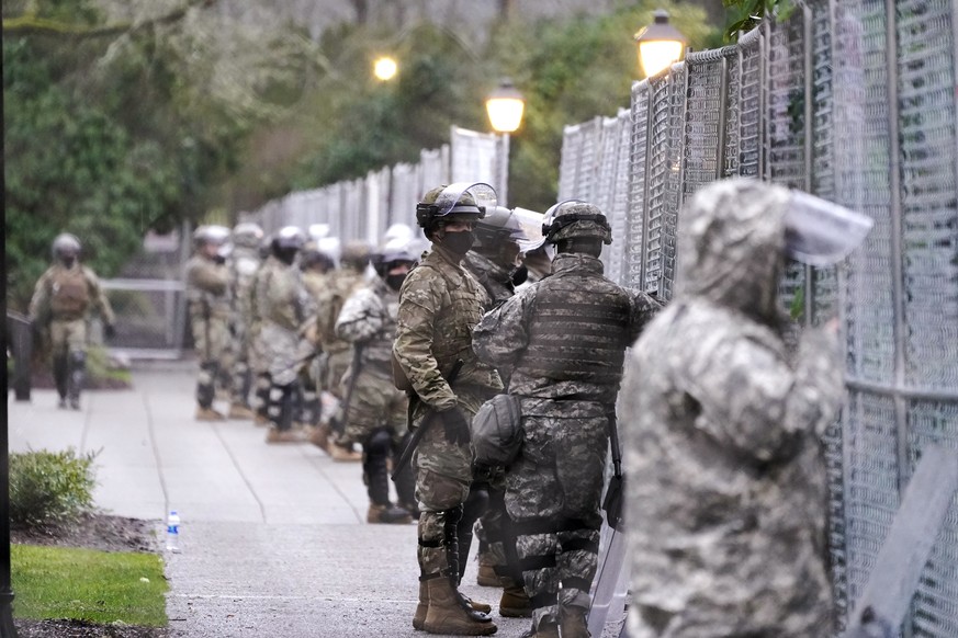 Members of the Washington National Guard stand at a fence surrounding the Capitol in anticipation of protests Monday, Jan. 11, 2021, in Olympia, Wash. State capitols across the country are under heigh ...