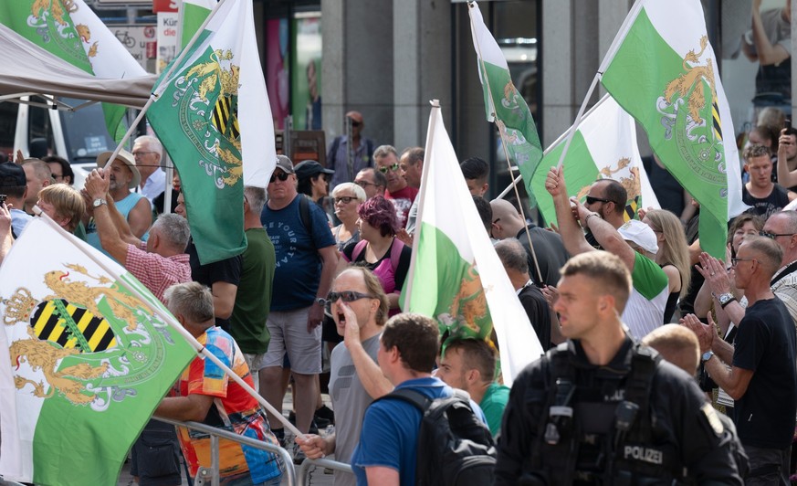 30.08.2024, Sachsen, Chemnitz: Teilnehmer einer Protestkundgebung der Partei &quot;Freie Sachsen&quot; stehen am Rande des Wahlkampfabschlusses der SPD in Chemnitz. Am 1. September finden in Sachsen d ...