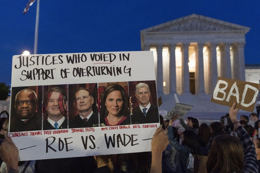 FILE - Nikki Tran of Washington, holds up a sign with pictures of Supreme Court Justices Thomas, Kavanaugh, Samuel Alito, Amy Coney Barrett, and Neil Gorsuch, as demonstrators protest outside of the U ...