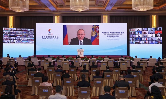 23.06.2022, China, Peking: Auf diesem von der chinesischen Nachrichtenagentur Xinhua ver�ffentlichten Foto h�lt Wladimir Putin (Monitor), Pr�sident von Russland, bei der Er�ffnungszeremonie des BRICS- ...